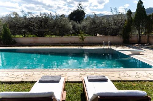 a swimming pool with two lounge chairs in the grass at Gustav Retreat Villa in Goumaíika