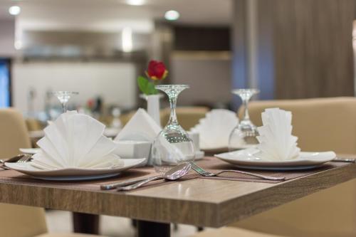 a wooden table with plates and glasses and napkins at Enala Hotel - Al Khobar in Al Khobar