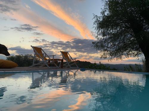 zwei Stühle neben einem Pool bei Sonnenuntergang in der Unterkunft La Linda de la Aldea Serrana in La Falda