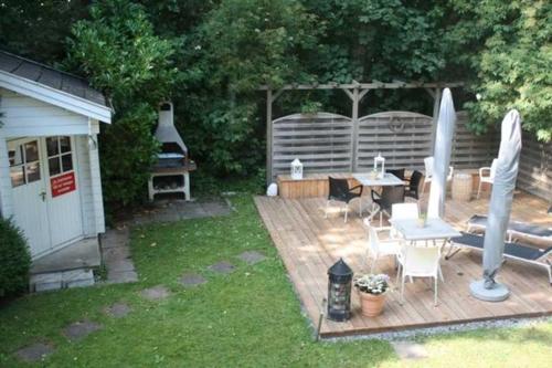 a backyard with a wooden deck with a table and umbrella at Gaestehaus Denecke in Scharbeutz