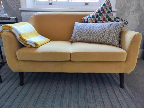 a yellow couch with pillows on top of it at Merchant House in Bootle