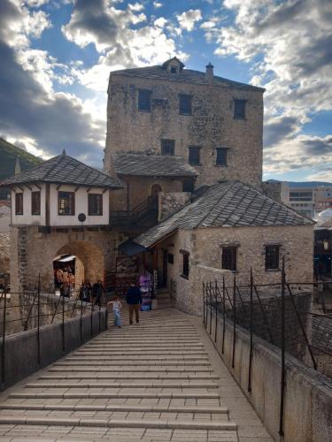 a group of people walking down a bridge in front of a castle at Apartman Miletic in Mostar