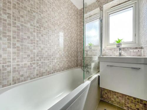 Baño blanco con bañera y lavamanos en New Cosy Luxury 3 Bedroom House in Battersea London en Londres