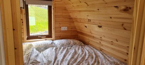 a bedroom with a bed in a wooden wall at Fairhead Glamping Pods in Ballycastle
