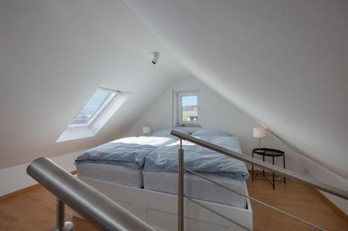 a white bedroom with a bed in a attic at Ferienwohnung Julia - klimatisiert in Wolken