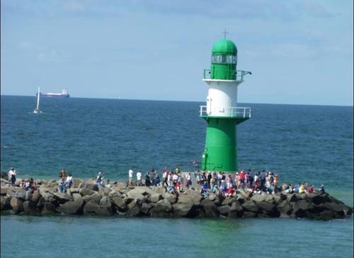 a green and white lighthouse on the rocks in the water at Birnbom Warnemünde in Warnemünde