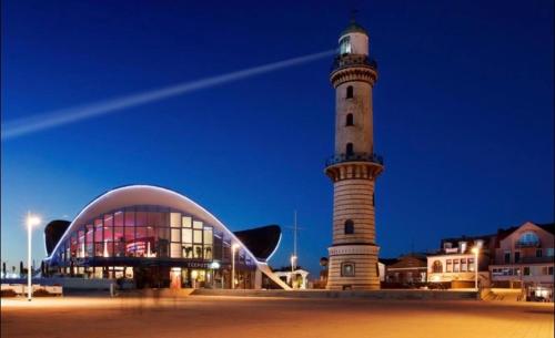 a lighthouse in front of a building and a building at Birnbom Warnemünde in Warnemünde