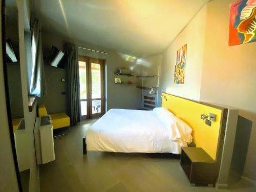 um quarto com uma cama branca e uma parede amarela em Vela di Soleville camere con e senza vista lago con ristorante & pizzeria em Sale Marasino