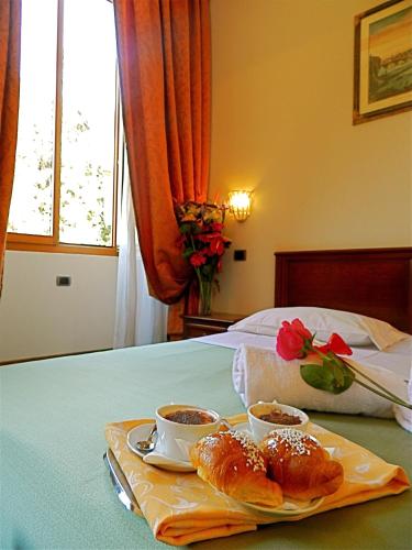 een dienblad met croissants en kopjes koffie op een bed bij Domus Florentiae Hotel in Florence