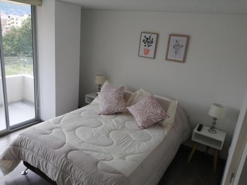 a bedroom with a bed with pillows and a window at Lujoso Apartamento Cerca al Lago Sochagota en Paipa in Paipa