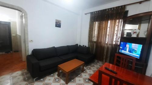 a living room with a black couch and a tv at Lovely appartament B in Tirana