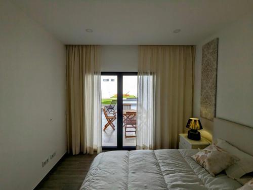 a bedroom with a bed and a view of a patio at Ria Breez'in by JohnVillas in Alvor