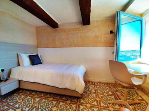 a bedroom with a bed and a chair and a window at Cove 532 by Savynomad Harbour Residences wow View in Valletta