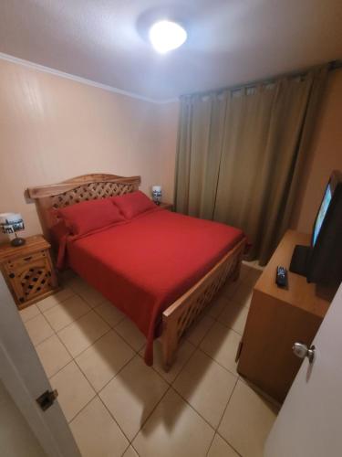 a bedroom with a red bed and a television at Arriendo Departamento Diario en Copiapo in Copiapó