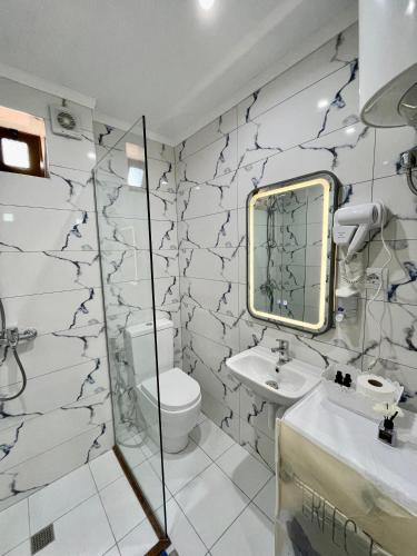 a bathroom with a toilet and a sink and a mirror at GUGA Host House in Sarandë