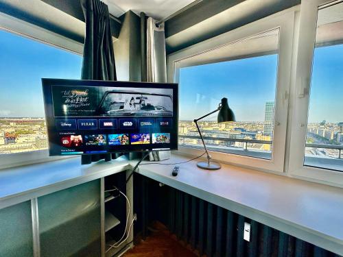 a television sitting on a desk in front of two windows at Super Apartament GREY Centrum 2x Metro Fast WiFi 300 Mbs Netflix AppleTV SmartTV Spotify Panorama Miasta in Warsaw