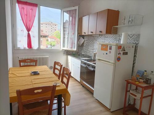 Appartamento in bassa montagna a Bussoleno في Bussoleno: مطبخ مع طاولة وثلاجة بيضاء