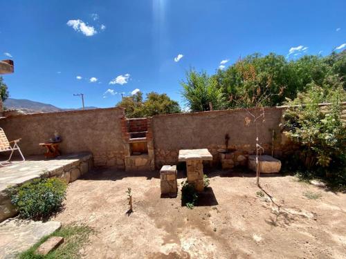 um quintal com uma parede de pedra e uma mesa em Hospedaje Fortaleza Indigena em Tilcara