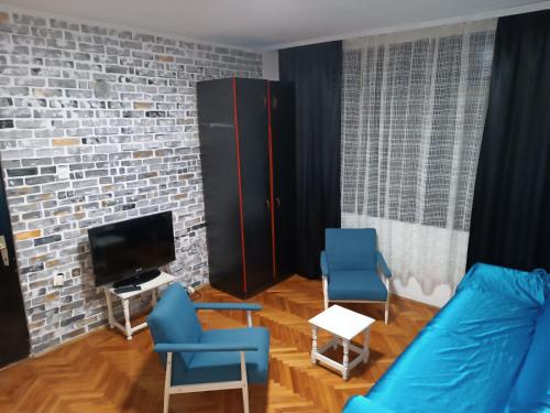 a living room with two blue chairs and a tv at Kuršumlijska banja apartman in Kuršumlija