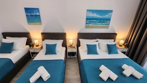 2 camas en una habitación con almohadas azules y blancas en Solar Rooms and Apartments, en Himare