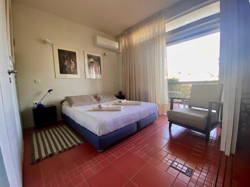 a bedroom with a bed and a chair and a window at Argyro suite Rafina in Rafina