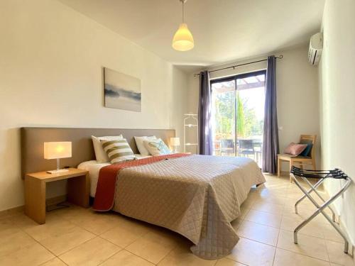 a bedroom with a bed with a lamp and a window at Golf Villa Alvor By CORAL in Alvor
