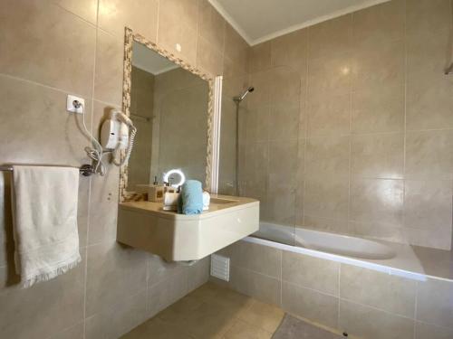 uma casa de banho com um lavatório, uma banheira e um espelho. em Golf Villa Alvor By CORAL em Alvor