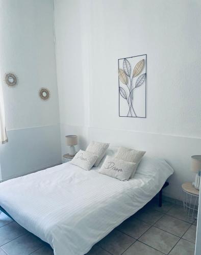 un lit blanc avec deux oreillers dessus dans l'établissement Appartement authentique coeur de ville sete, à Sète