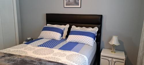 Schlafzimmer mit einem Bett mit blauen und weißen Kissen in der Unterkunft Bédard in Gatineau