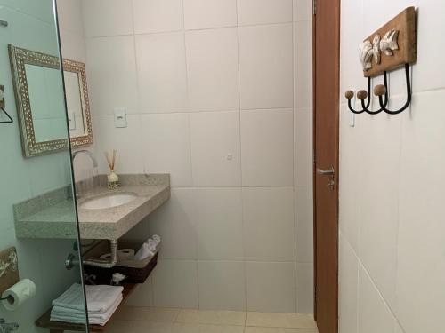 a bathroom with a sink and a shower with a mirror at Paraiso Pe na Areia entre Ilhéus e Itacare in Ilhéus