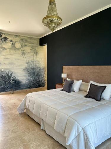 a bedroom with a large white bed with a chandelier at Casimiro Ibera Hotel Boutique in Colonia Carlos Pellegrini
