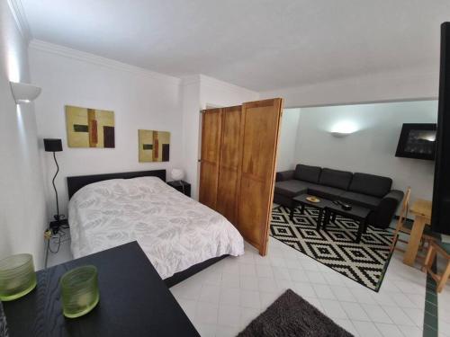 a bedroom with a bed and a couch and a desk at Charming Beachside Apartment- The Perfect Getaway! in Albufeira