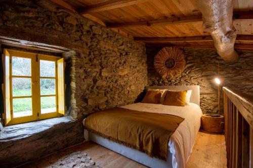 a bedroom with a bed in a stone wall at Lagos Com Sabor Guest House 