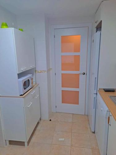 a kitchen with a white door and a microwave at APARTAMENTO MANUELA PROXIMO a GOLF ISLA CANELA LINKS in Ayamonte