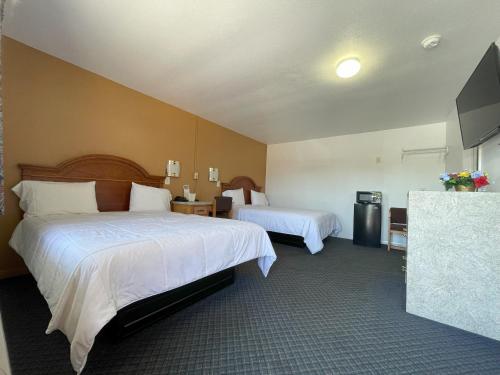 Habitación de hotel con 2 camas y TV de pantalla plana. en El Camino Motel, en Tallahassee