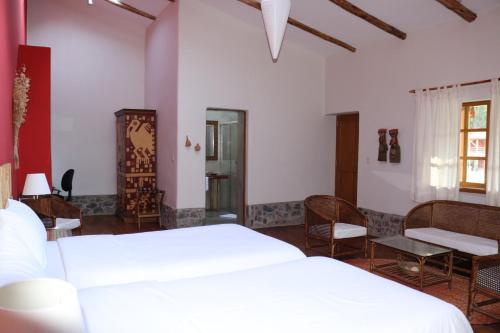 a bedroom with two beds and a table and chairs at Hotel Villa Urubamba in Urubamba