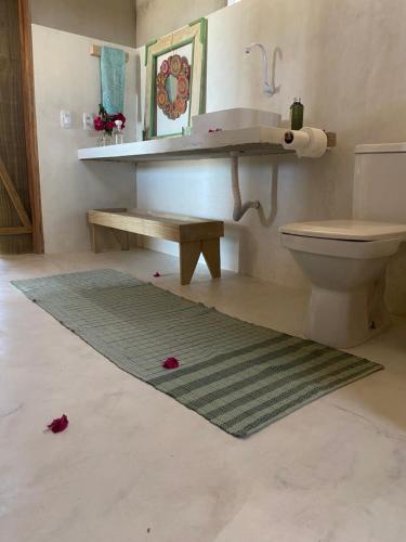 baño con aseo, banco y alfombra en Cabana Cachandó en Corumbau