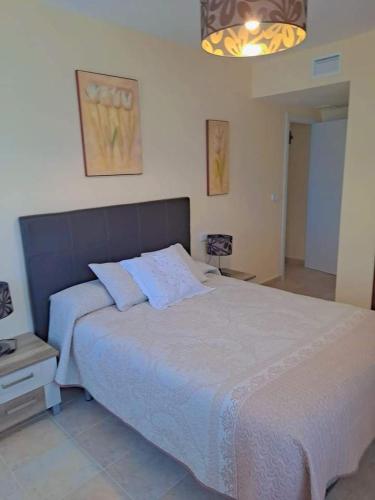 a bedroom with a large white bed and a light at APARTAMENTO MANUELA PROXIMO a GOLF ISLA CANELA LINKS in Ayamonte