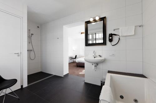 a white bathroom with a sink and a mirror at College Hotel Alkmaar in Alkmaar