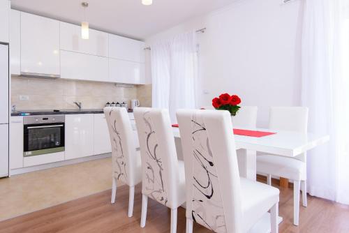 a white kitchen with a table and white chairs at Apartment Violeta 1 with private terrace in Dubrovnik