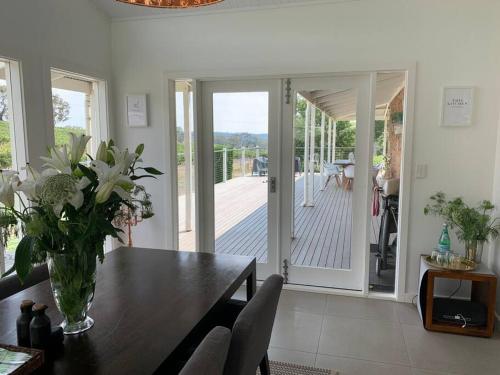 a dining room with a vase of flowers on a table at O'Briens of Clare - Stylish Pet Friendly Vineyard Accommodation in Clare