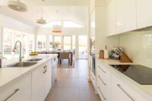 a kitchen with white cabinets and a dining room at O'Briens of Clare - Stylish Pet Friendly Vineyard Accommodation in Clare