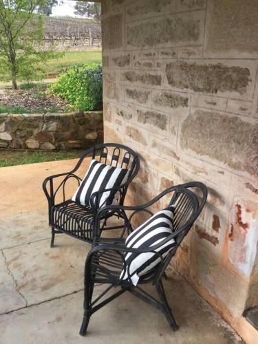 two black and white chairs sitting next to a stone wall at O'Briens of Clare - Stylish Pet Friendly Vineyard Accommodation in Clare