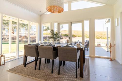 a dining room with a table and chairs and windows at O'Briens of Clare - Stylish Pet Friendly Vineyard Accommodation in Clare