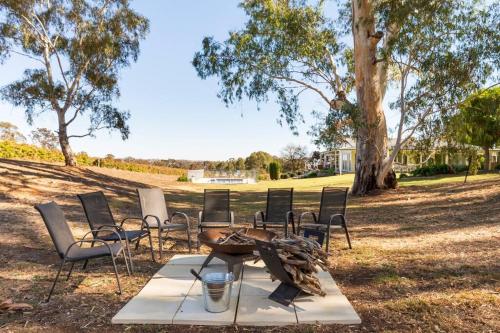 a picnic table and chairs in a park with a tree at O'Briens of Clare - Stylish Pet Friendly Vineyard Accommodation in Clare
