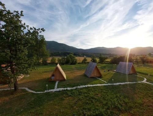 a group of tents in a field with the sunset at Lika Sunset in Ličko Lešće