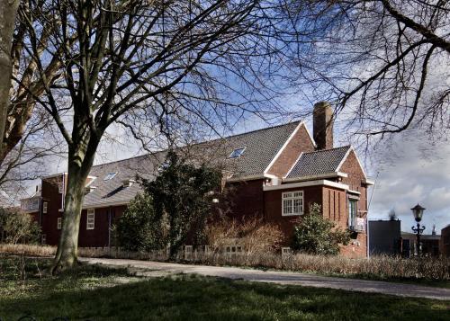 a brown house with a tree in front of it at College Hotel Alkmaar in Alkmaar