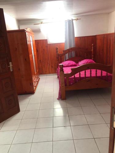 - une chambre avec un lit en bois et des draps roses dans l'établissement Aka Kikine, à Sainte-Anne