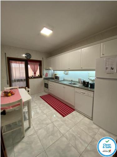 a kitchen with white cabinets and a table and a red rug at Oporto Cavadas House in Porto