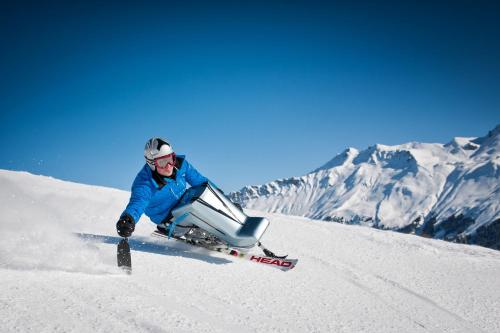 a man is skiing down a snow covered mountain at Berghotel Tgantieni in Lenzerheide